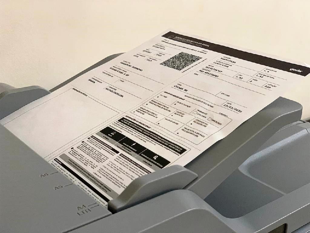 Imagem de uma impressora com uma folha de papel contendo dados do licenciamento MT 2024